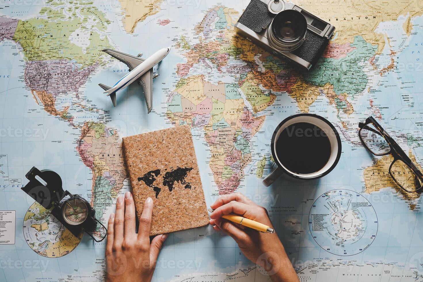 Top view of young woman planning her vacation using world map - Travel  influencer looking for the next travel destination - Concept of adventure, tourism, and traveling people lifestyle photo