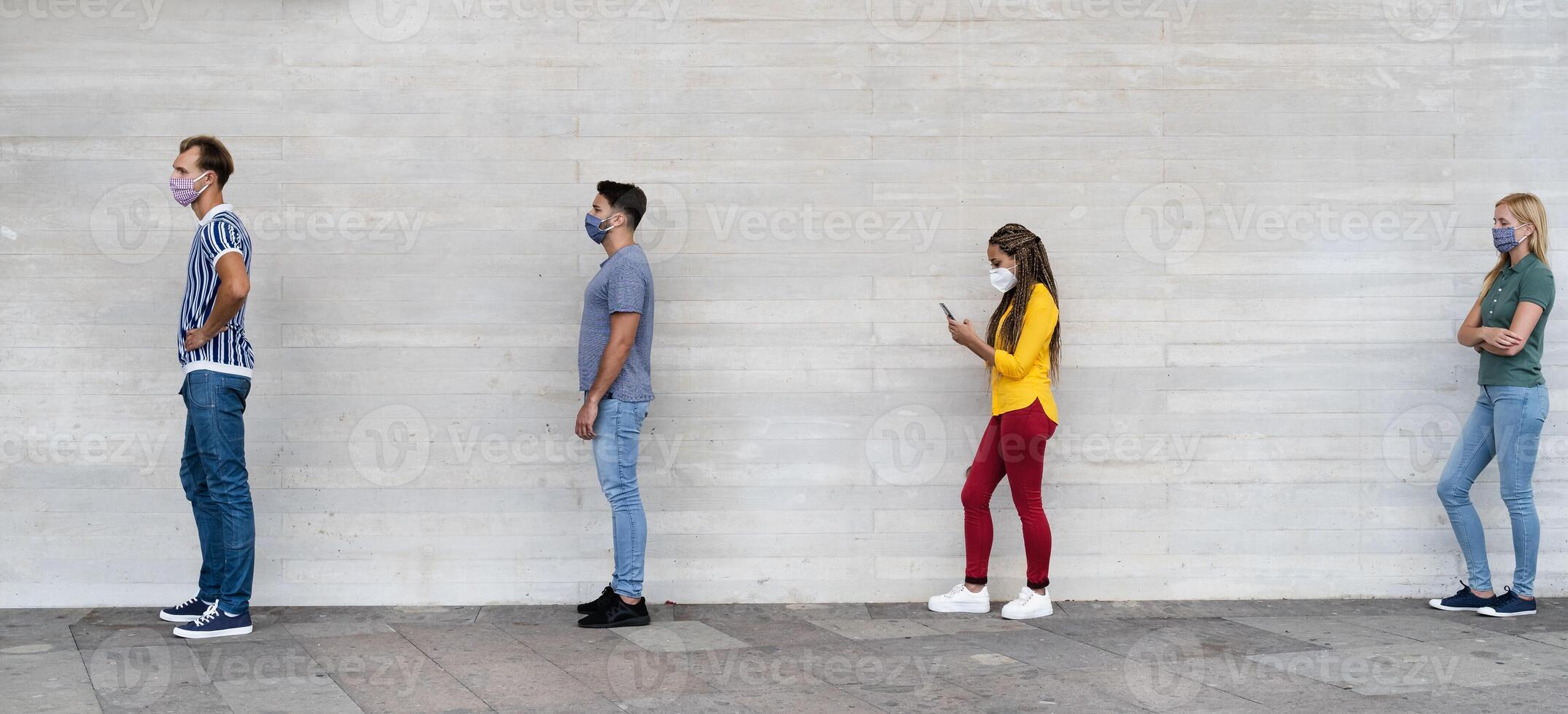 Young people from different cultures and race waiting in queue outside shop market while keeping social distance - Corona virus spread prevention concept photo