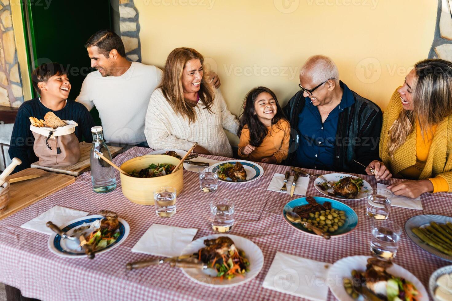contento latín familia teniendo divertido almorzando juntos a hogar foto