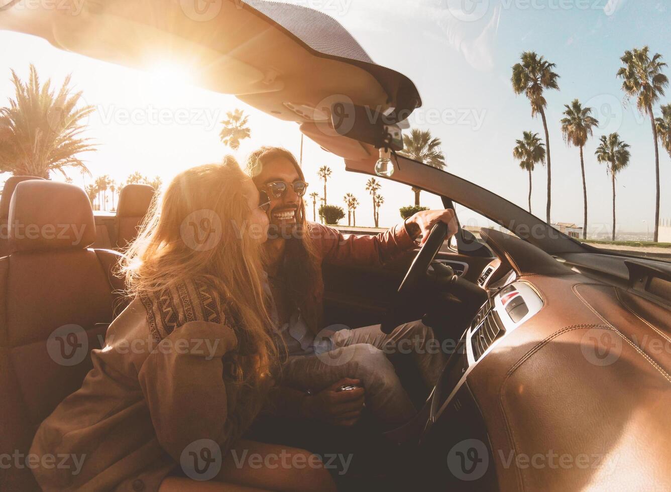 Happy young couple doing road trip in tropical city - Travel people having fun driving in trendy convertible car discovering new places - Relationship and youth vacation lifestyle concept photo