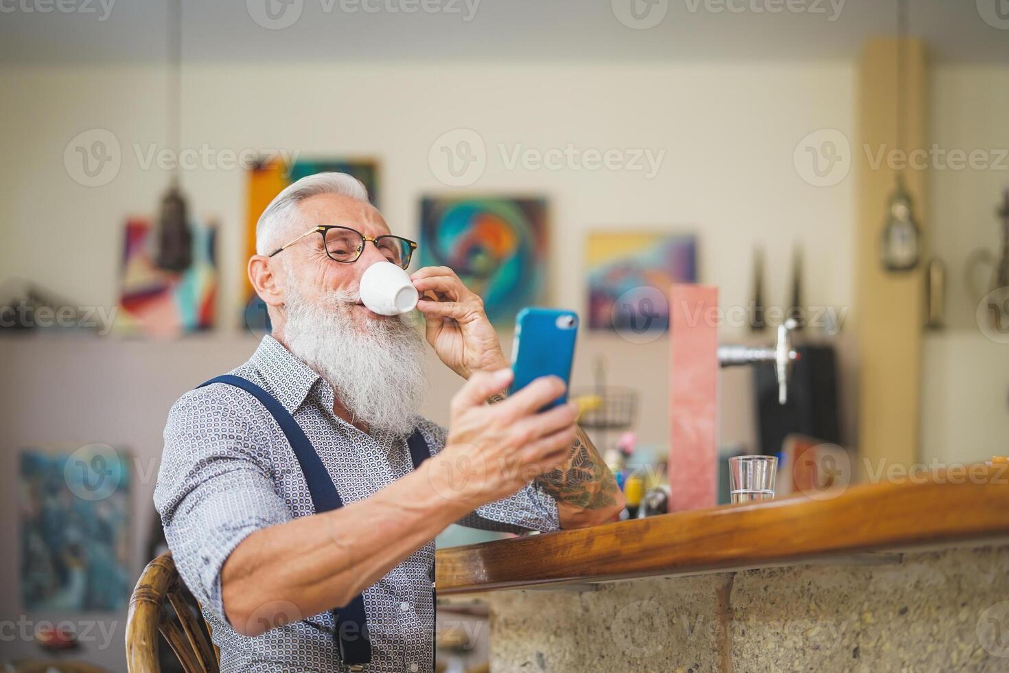 Senior man using mobile smartphone while drinking coffee in bar restaurant - Technology and elderly people lifestyle concept photo