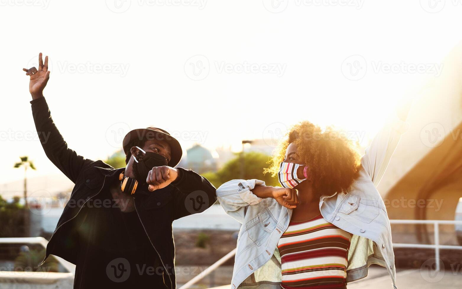 afro americano amigos vistiendo cara protector máscara haciendo nuevo social distancia saludos golpeando codos - juventud milenario personas y salud cuidado pautas a evitar corona virus untado foto
