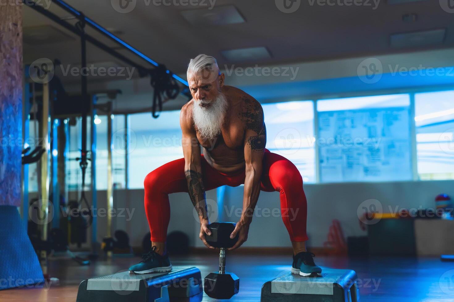 Senior man doing workout exercises inside gym - Fit mature male training in wellness club center - Body building and sport healthy lifestyle concept photo