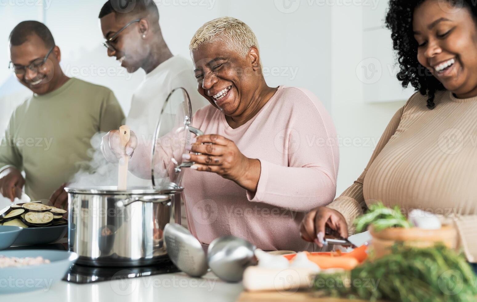 Happy black family having fun cooking together in modern kitchen - Food and parents unity concept photo