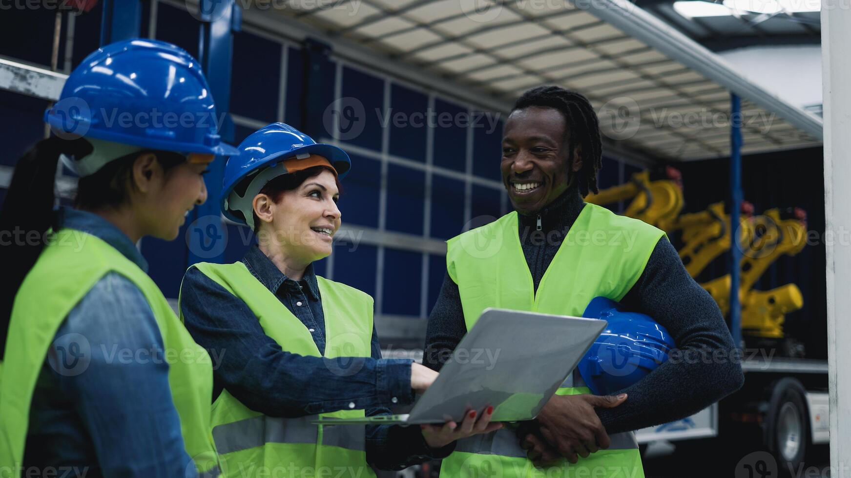 Team of multiracial engineers working in robotic factory monitoring the project on laptop - Tech industry concept photo