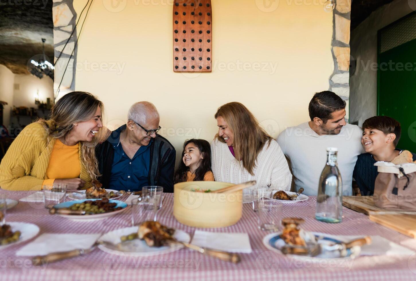 contento latín familia teniendo divertido almorzando juntos a hogar foto