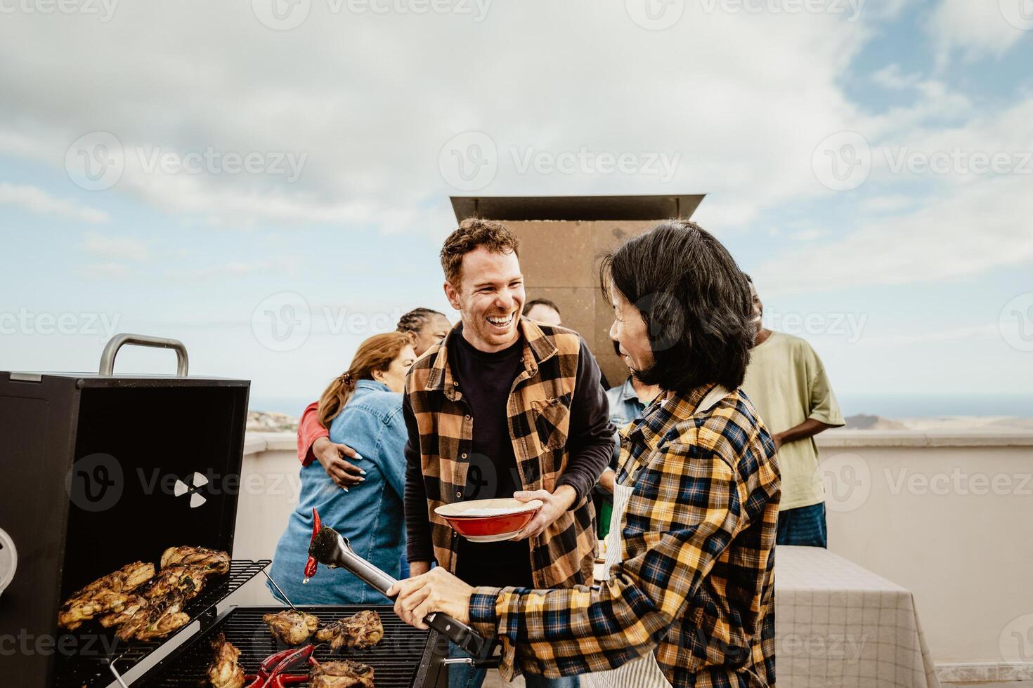 Happy multigenerational people having fun doing barbecue grill at house rooftop - Summer gatherings and food concept photo