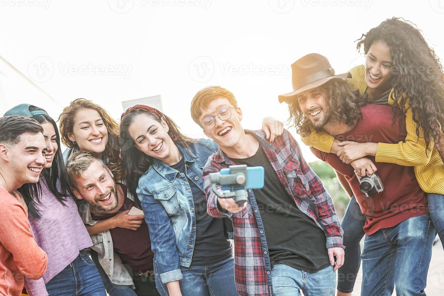 Happy trendy friends making video with gimbal smartphone camera in the city - Millennial young people having fun with new technology for social media network outdoor - Tech and youth lifestyle concept photo