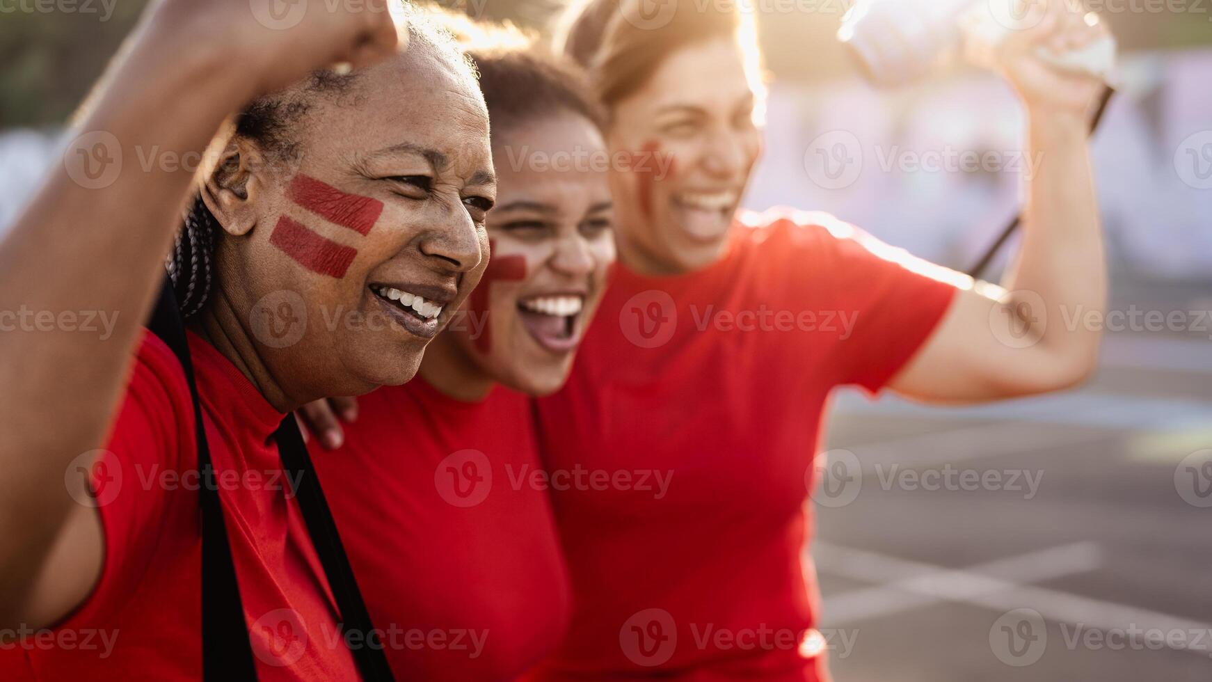 Female football fans exulting while watching soccer game at stadium - Women with painted face and megaphone encouraging their team - Sport entertainment concept photo