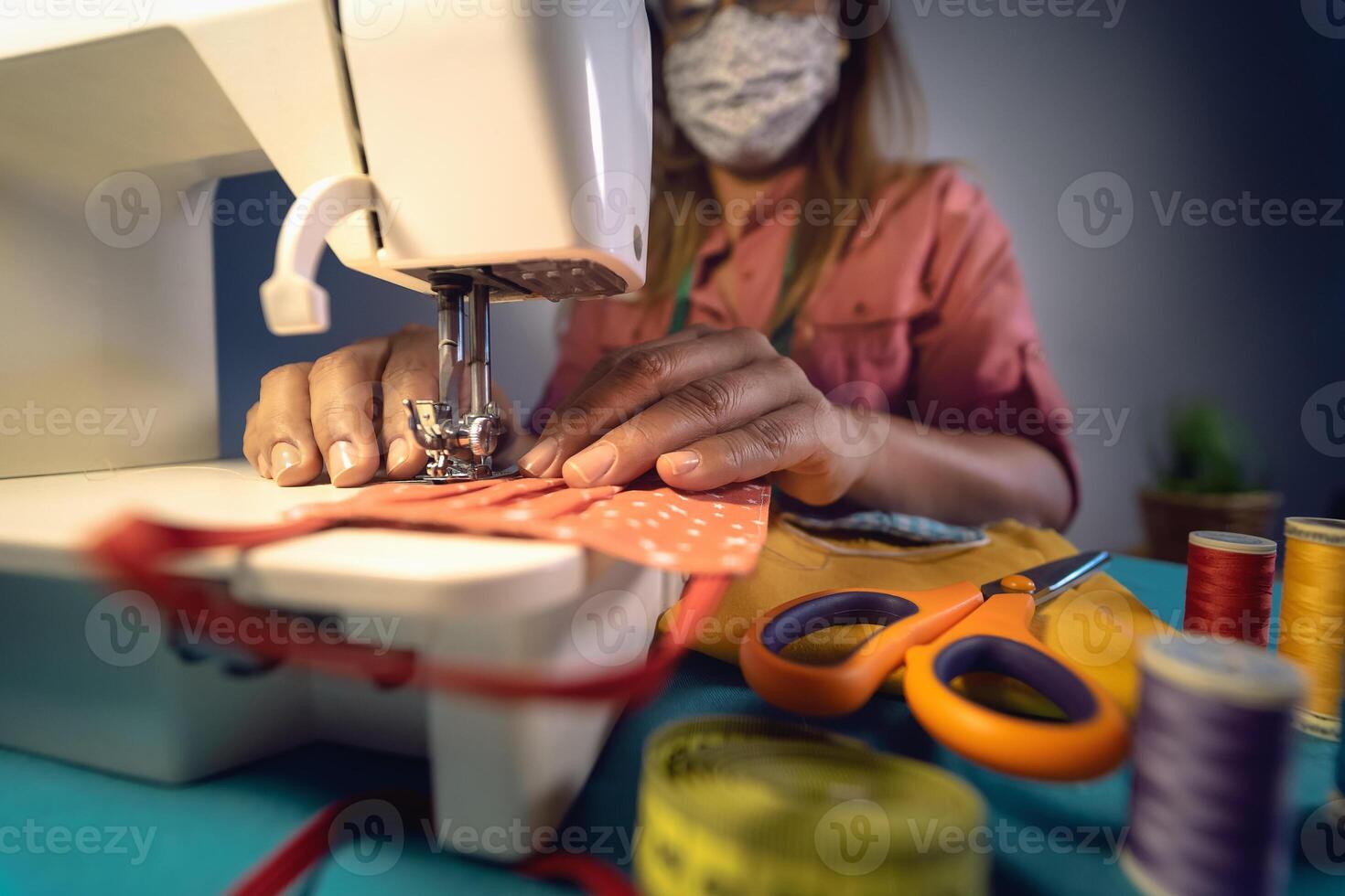 Close up Latin female hands sewing with sew machine homemade medical face mask for preventing and stop corona virus spreading - textile industry and covid19 healthcare concept photo