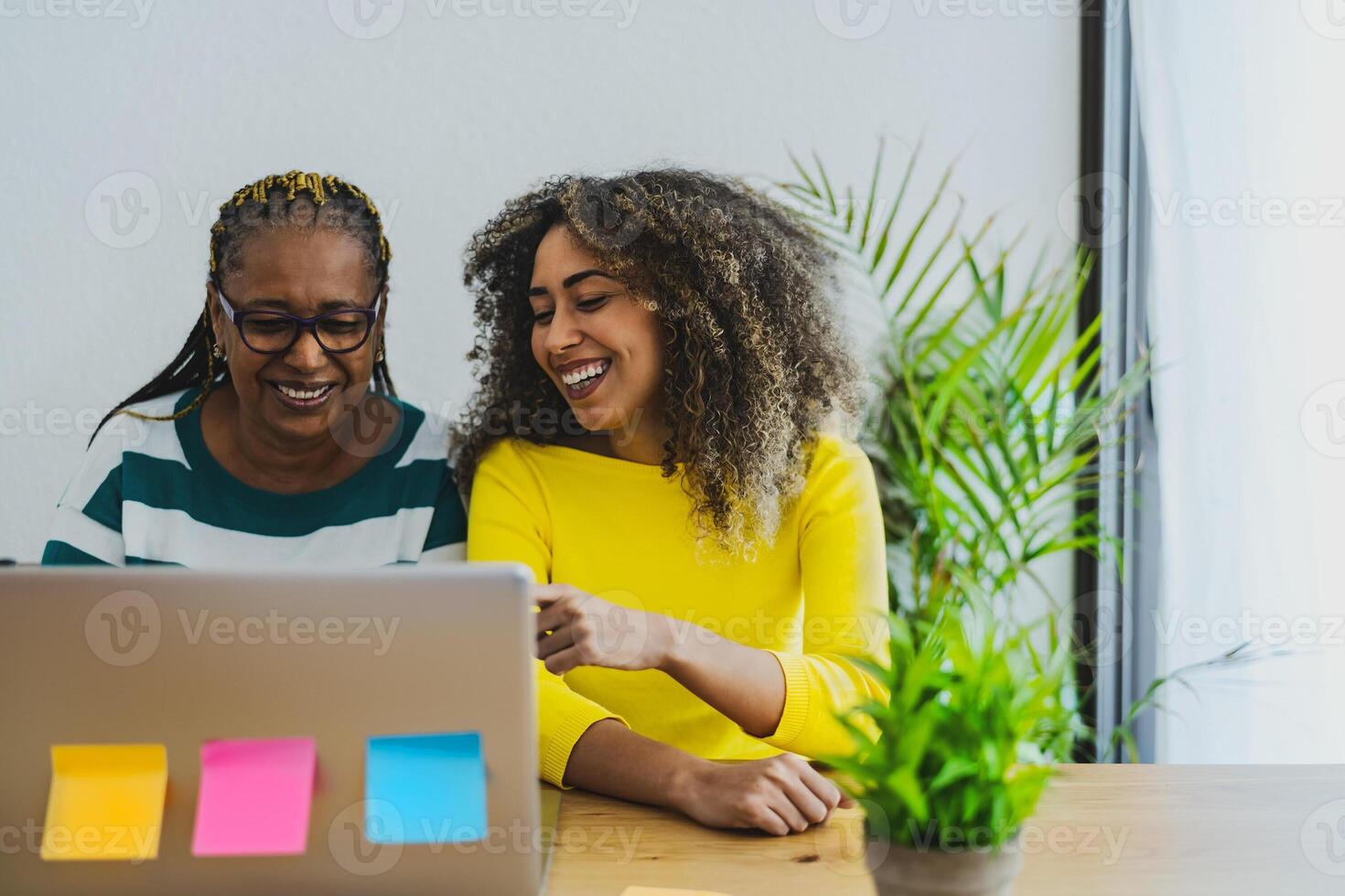 afro madre y hija teniendo divertido utilizando computadora para compras en línea - juventud y mayor personas con tecnología concepto foto