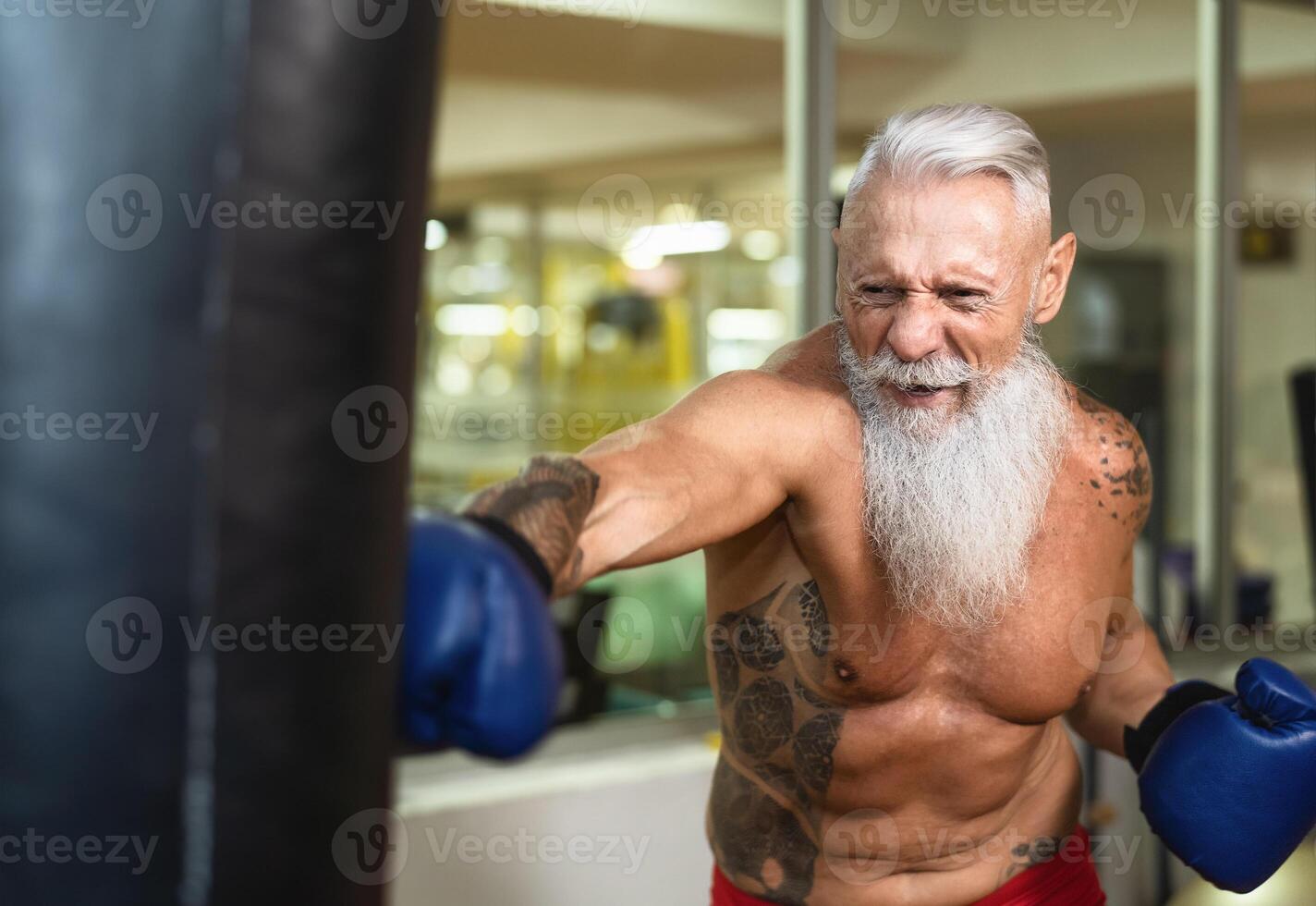 Senior man boxer training hard - Elderly male boxing in sport gym center club - Health fitness and sporty activity concept photo