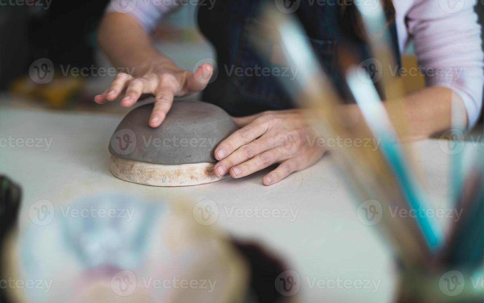 Close up female potter modeling clay bowl in workshop - Artisan work and creative craft concept photo