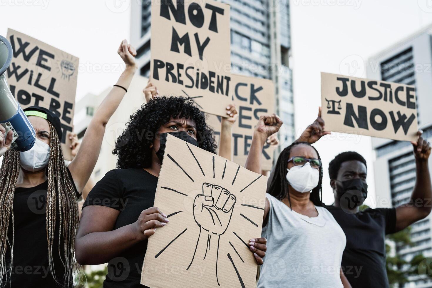 a group of people holding signs and wearing masks photo