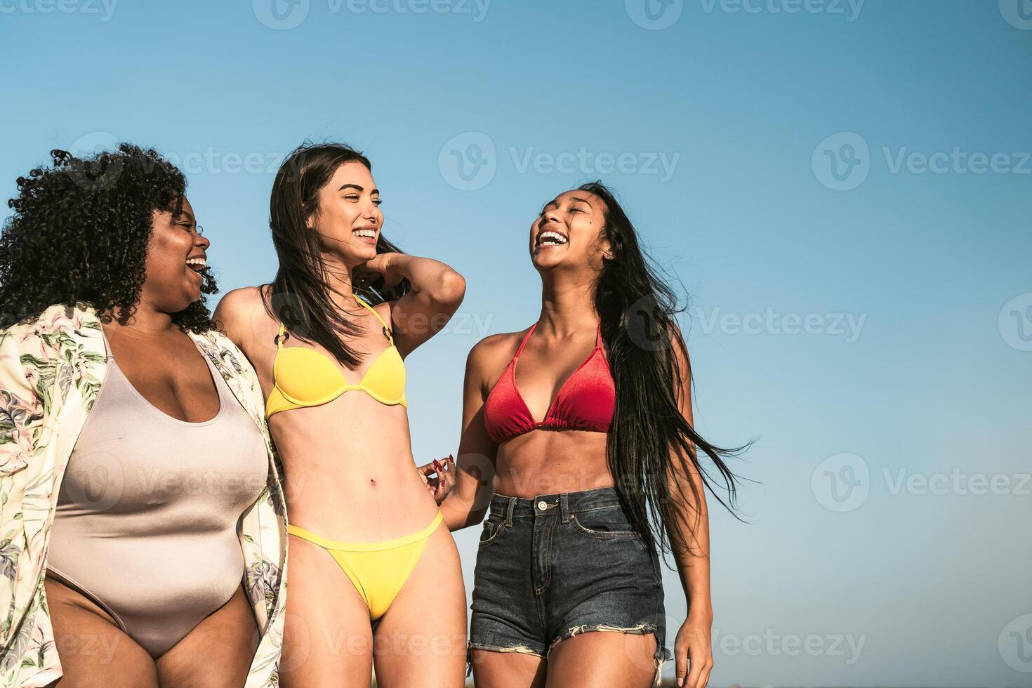 Happy multiracial females with different body size having fun walking on the beach during summer holidays photo