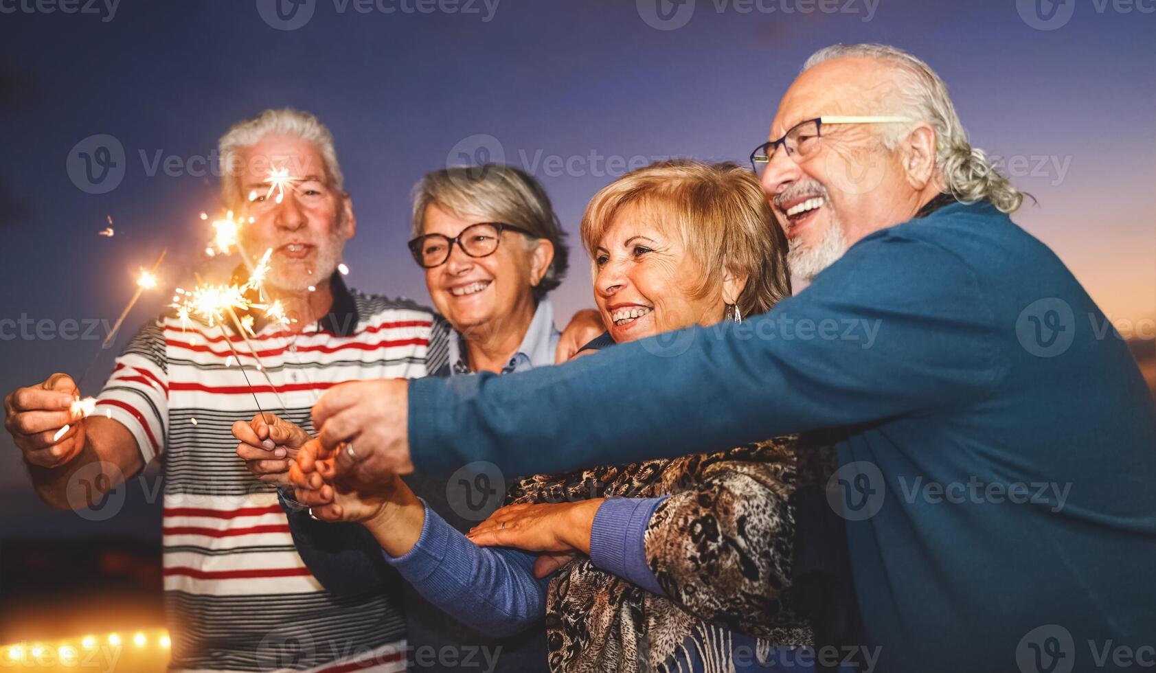 Happy senior family celebrating with sparkler fireworks at home party - Elderly people lifestyle and holidays concept photo