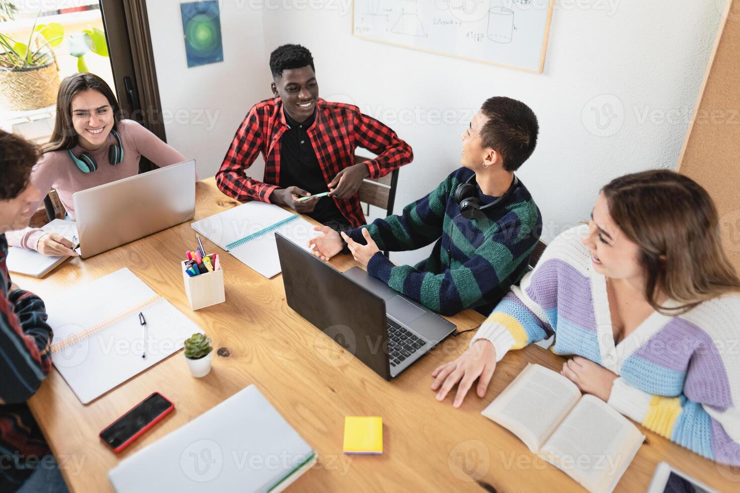 Young multiracial students reading books and using laptop in classroom while studying together -   School education concept - Focus on Asian guy photo