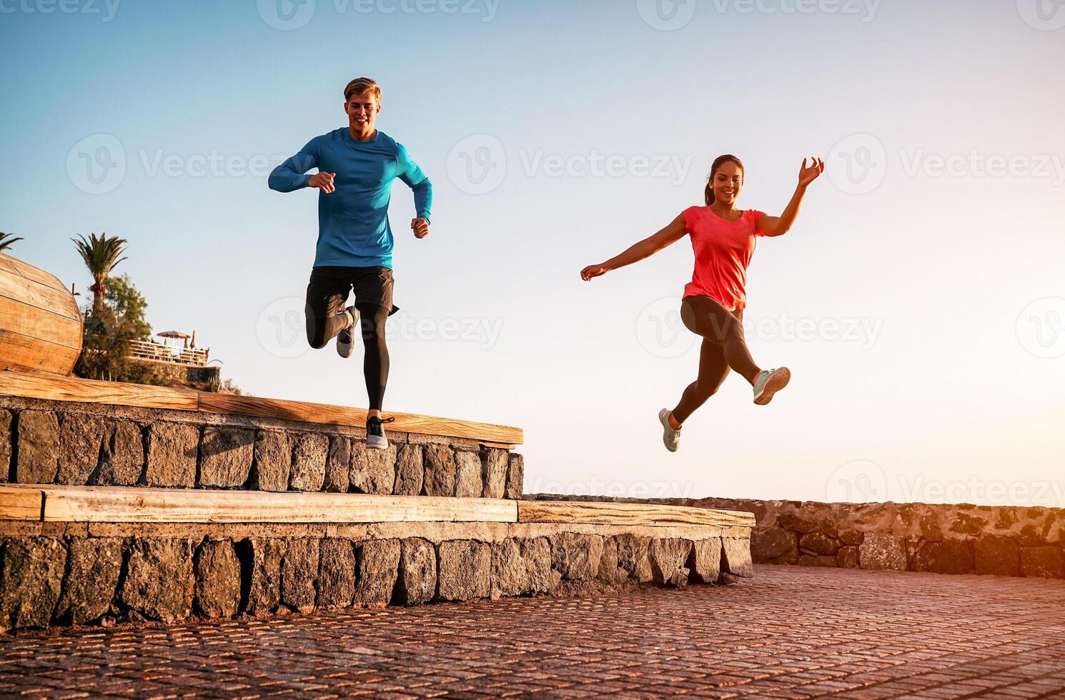 Fit couple doing workout running session at sunset outdoor - Sporty young people jogging next the beach - Healthy lifestyle and sport concept photo