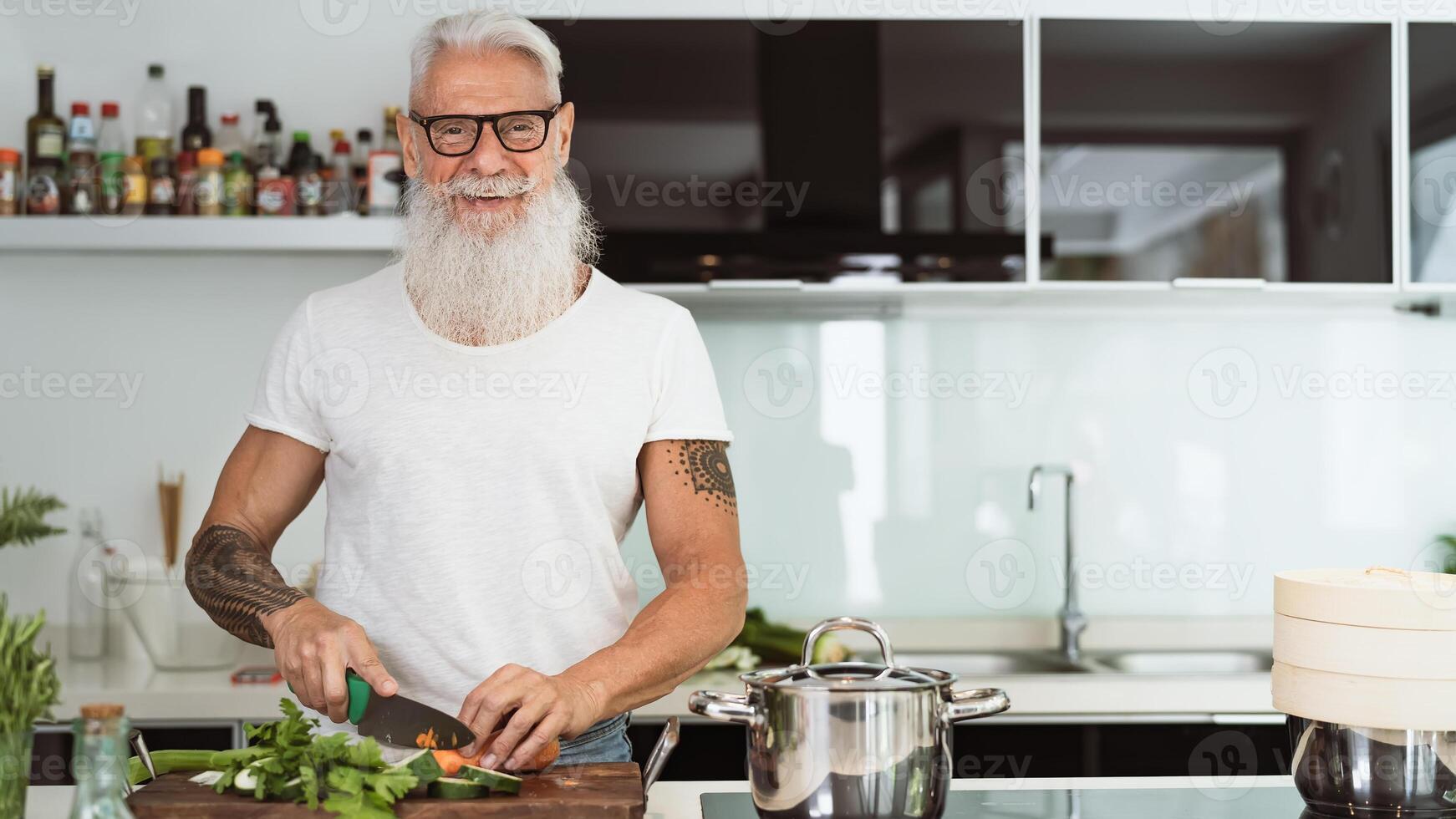 contento mayor hombre teniendo divertido Cocinando a hogar - mayor persona preparando salud almuerzo en moderno cocina - retirado estilo de vida hora y comida nutrición concepto foto