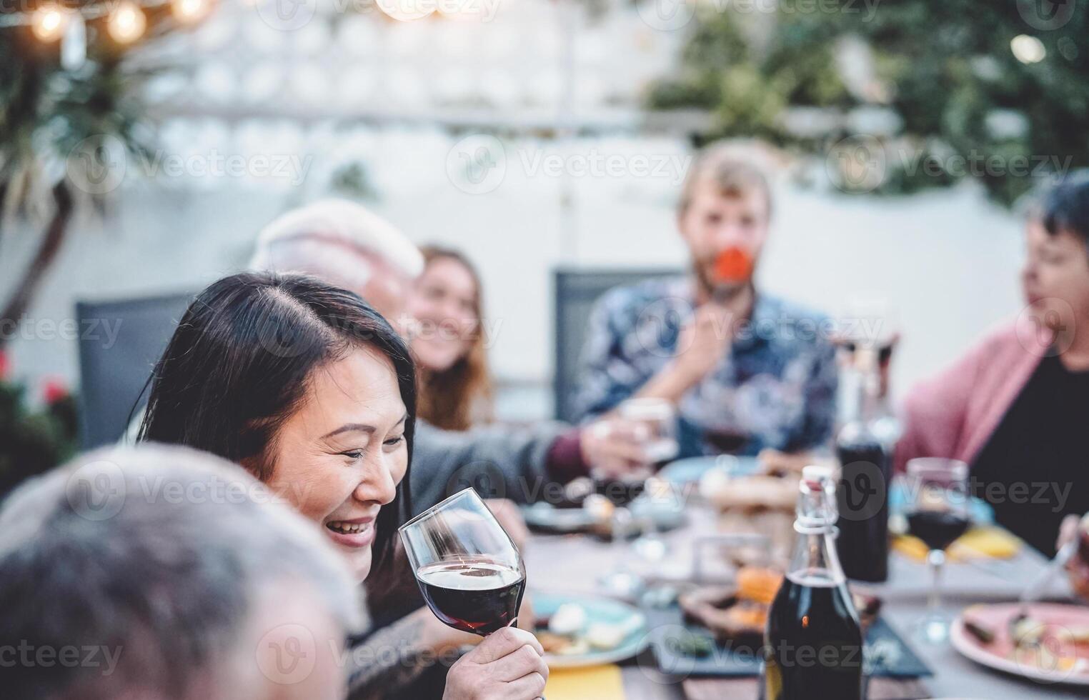 Happy family cheering and dining together outdoor - People with different ages and ethnicity having fun at barbecue dinner party - food and drink, retired and young people concept photo