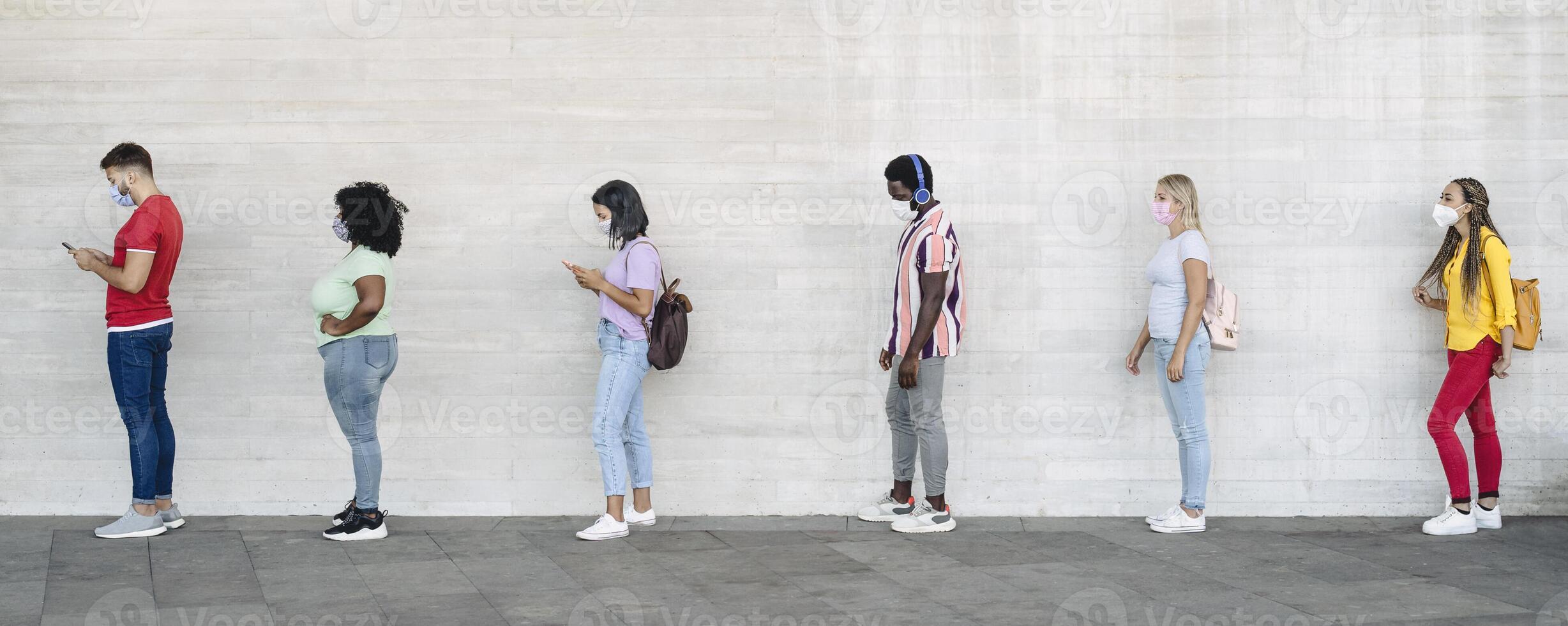 Young people from different cultures and race waiting in queue outside shop market while keeping social distance - Corona virus spread prevention concept photo
