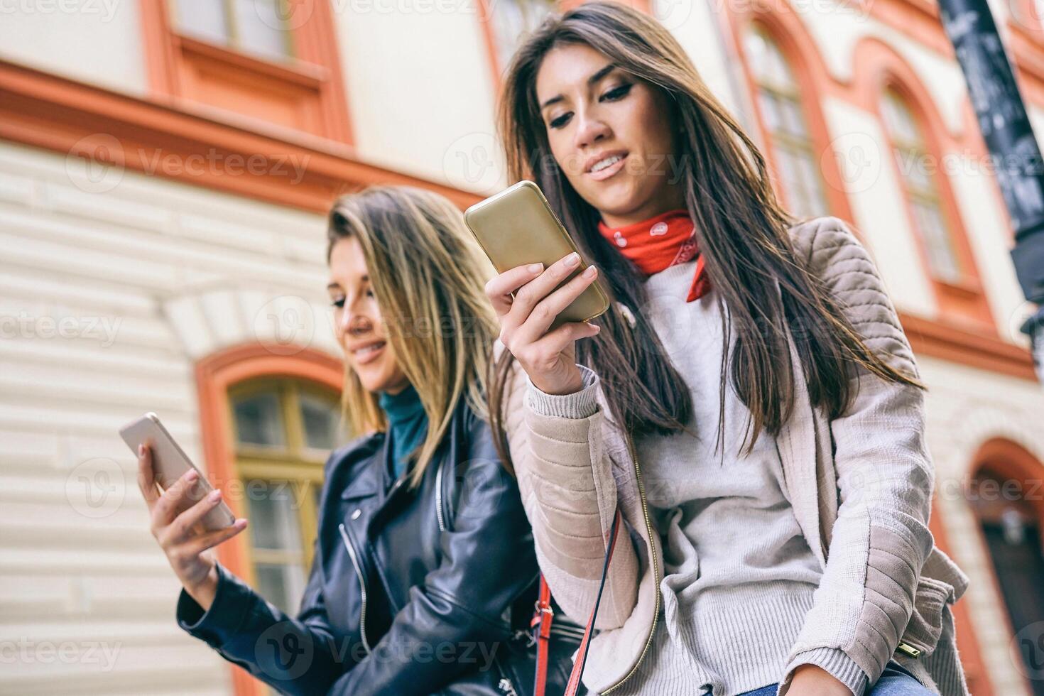 joven mujer en pie en un urbano zona utilizando móvil teléfono en el ciudad - contento amigos conectando en social medios de comunicación red al aire libre - personas fanático a nuevo teléfono inteligente tecnología - atención en mano en Derecha foto