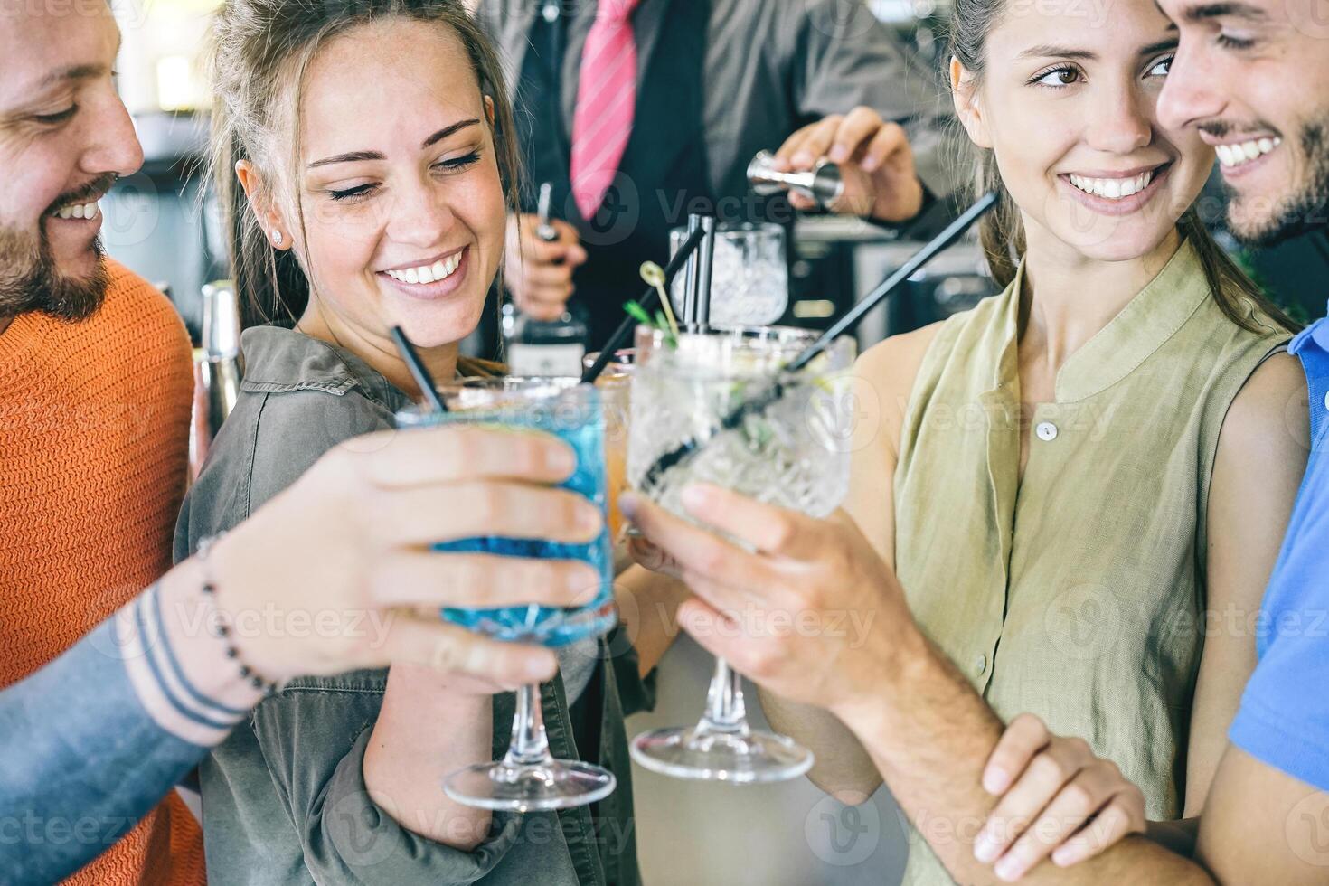 Two young couple in love toasting cocktails in a bar - Happy friends dating together making cheers with taste drinks - People, friendship, lifestyle and love concept - Focus on female photo