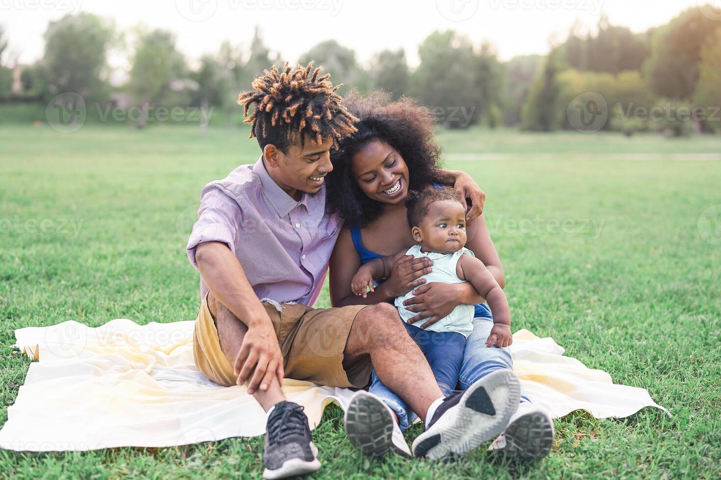 contento negro familia haciendo un picnic al aire libre - madre y padre teniendo divertido con su hija en un parque - amor y felicidad concepto foto