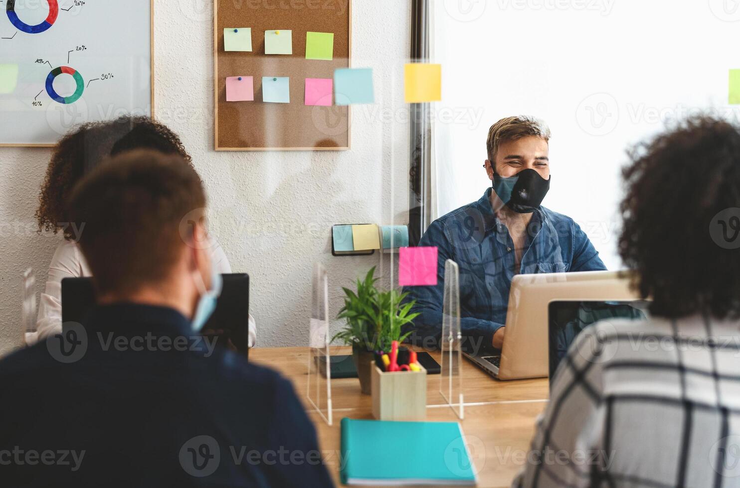 Young people in co-working creative space wearing surgical mask and keeping social distance to avoid corona virus spread - Health care and business technology concept photo