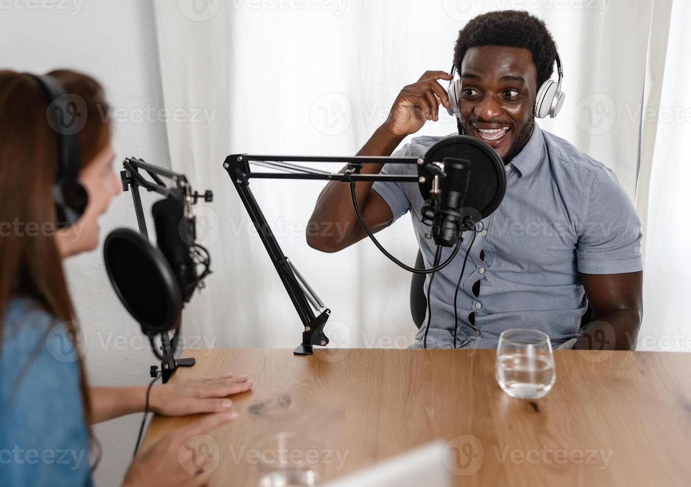 Multiracial people recording a podcast using microphone and headphones from home studio photo