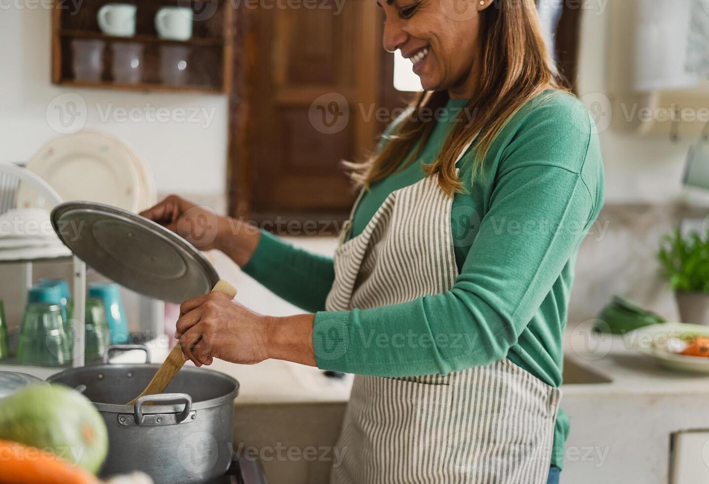 Latin mature woman cooking in old vintage kitchen - Smiling mother preparing lunch at home photo