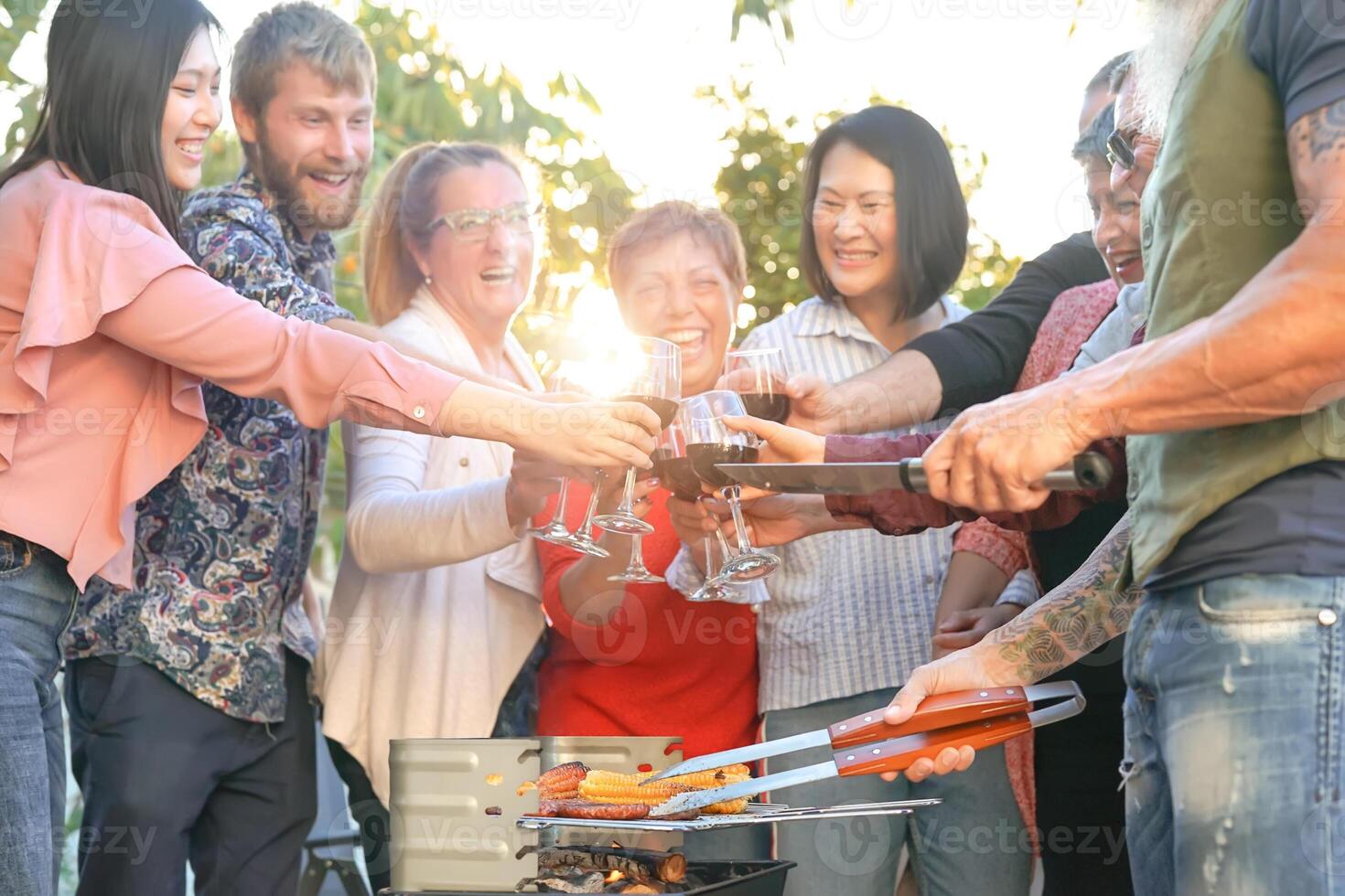 contento familia aplausos y tostado con rojo vino en parilla fiesta - cocinero mayor hombre interrogatorio intenso carne y teniendo con padres - fin de semana comida barbacoa y reunión joven y más viejo personas estilo de vida concepto foto