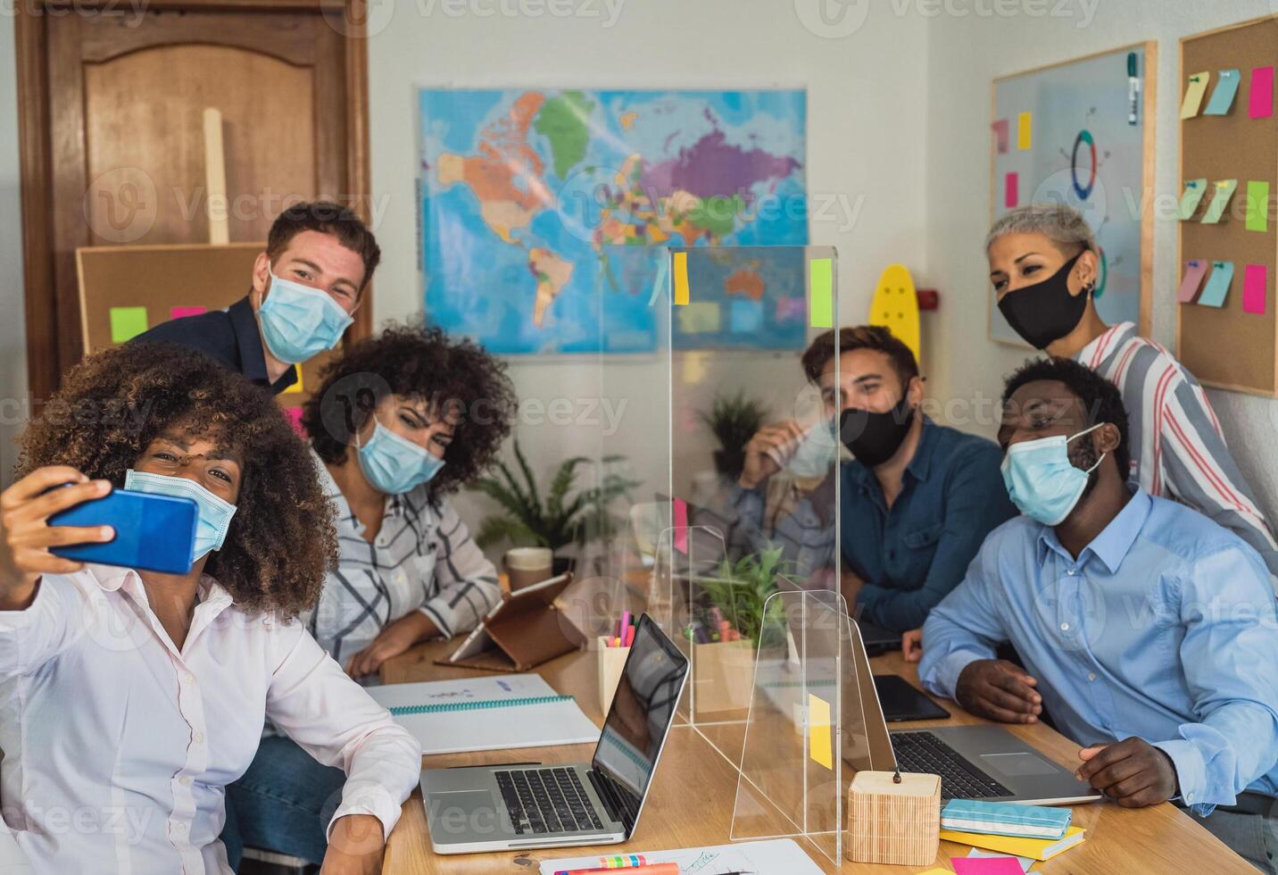 Young people in co-working creative space wearing surgical mask and taking selfie with mobile smartphone - Health care and business technology concept photo