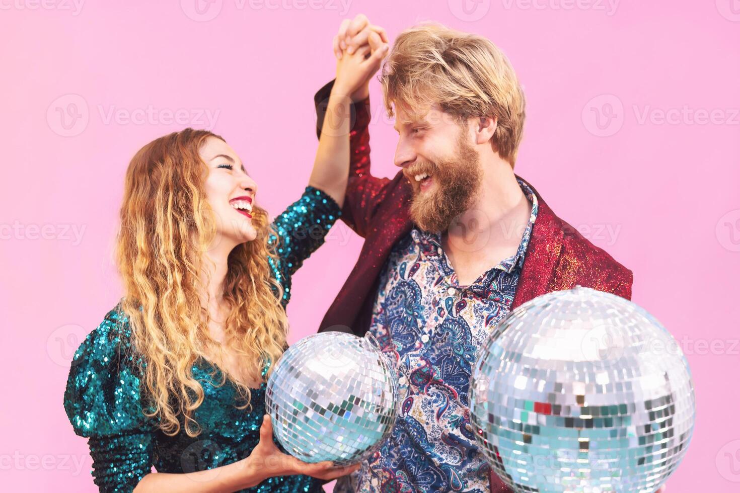 Happy couple celebrating valentines anniversary in disco club. Young trendy people having fun dancing together in nightclub. Love relationship and youth lifestyle holidays concept. Pink background photo