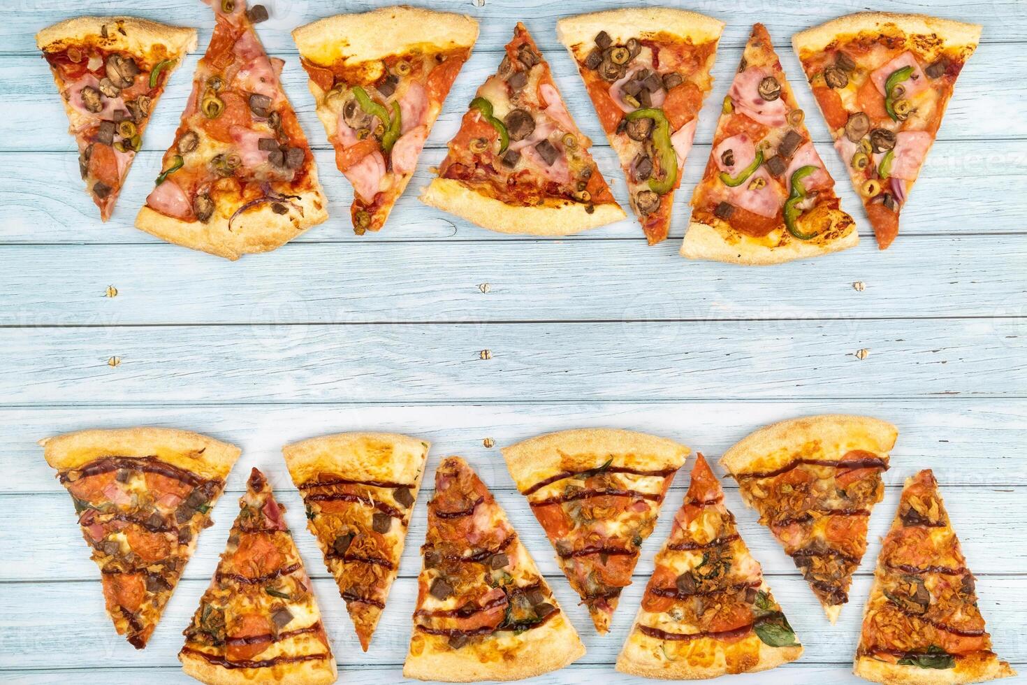 Lots of delicious triangular pizza slices on a blue wooden background photo