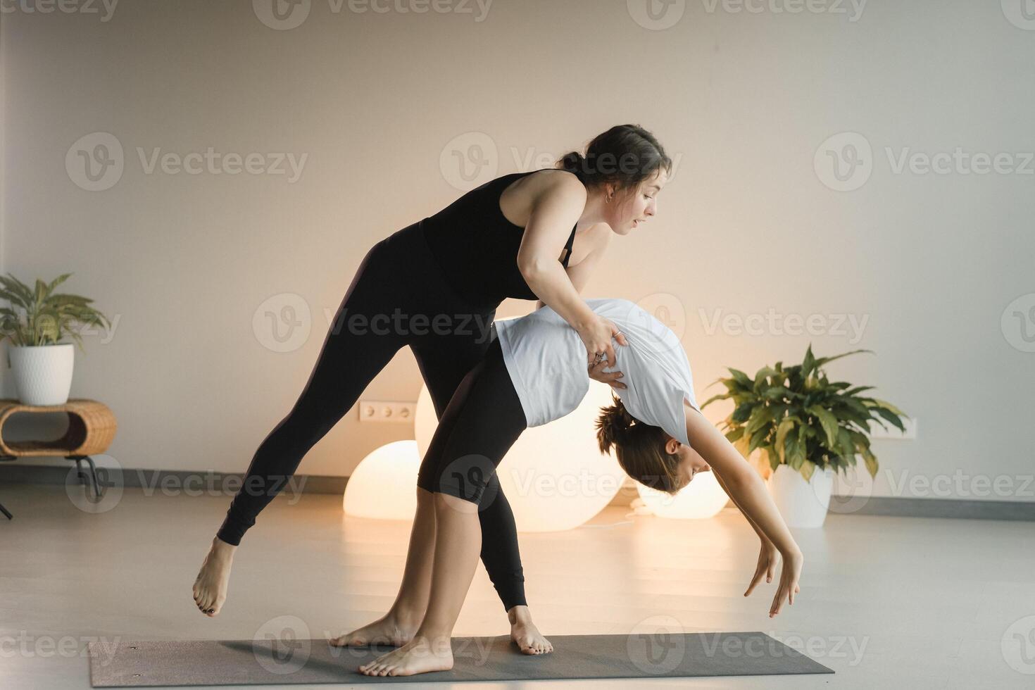 Mom and teenage daughter do gymnastics together in the fitness room. A woman and a girl train in the gym photo