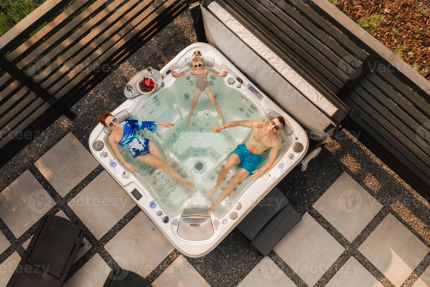 Top view of a family relaxing in an outdoor hot tub in summer photo