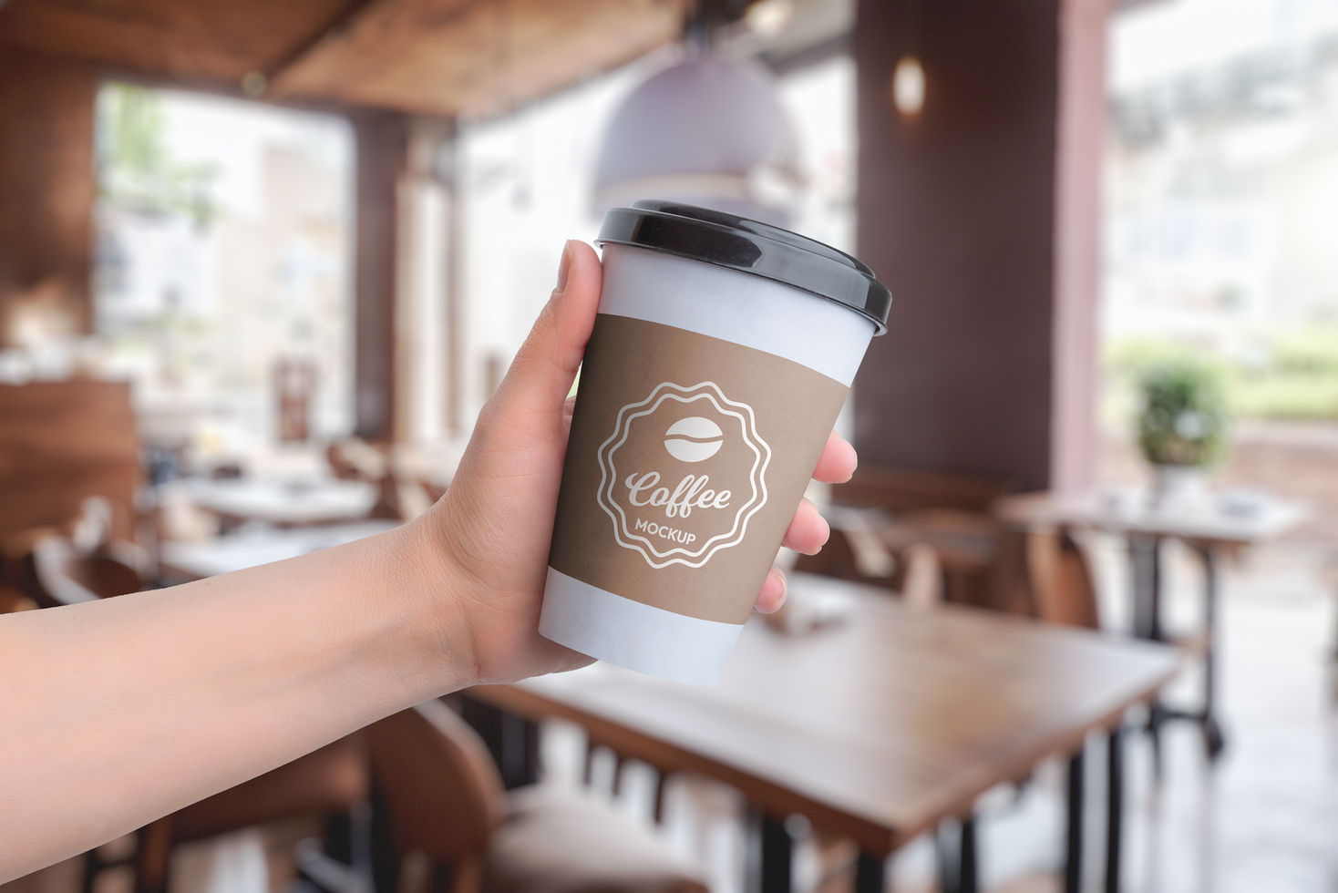 Paper cup mockup, held in hand at a coffee shop psd