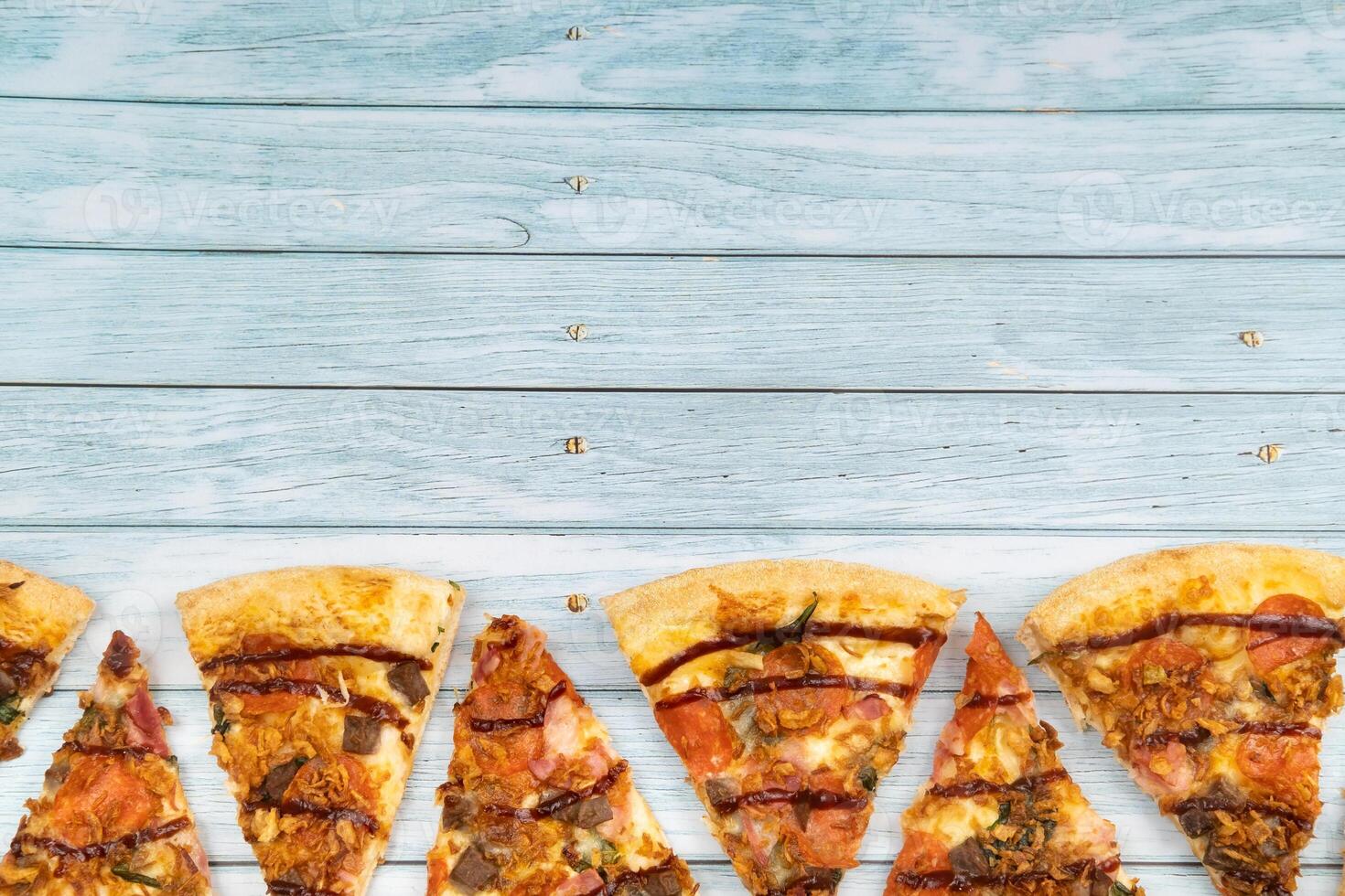 Lots of delicious triangular pizza slices on a blue wooden background photo