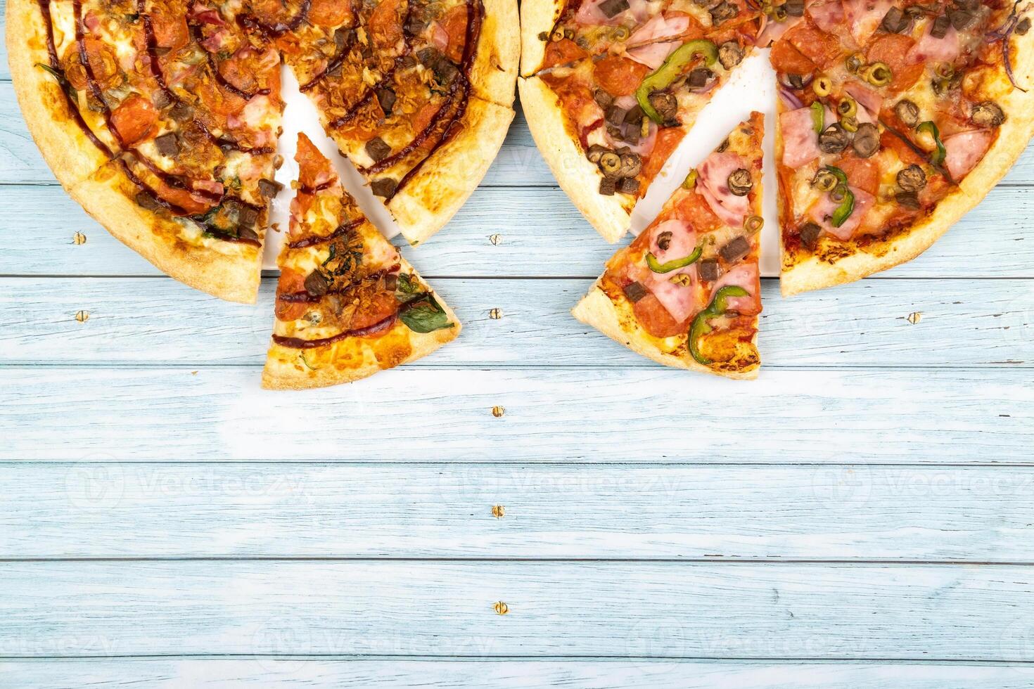 Two different delicious big pizzas on a blue wooden background photo