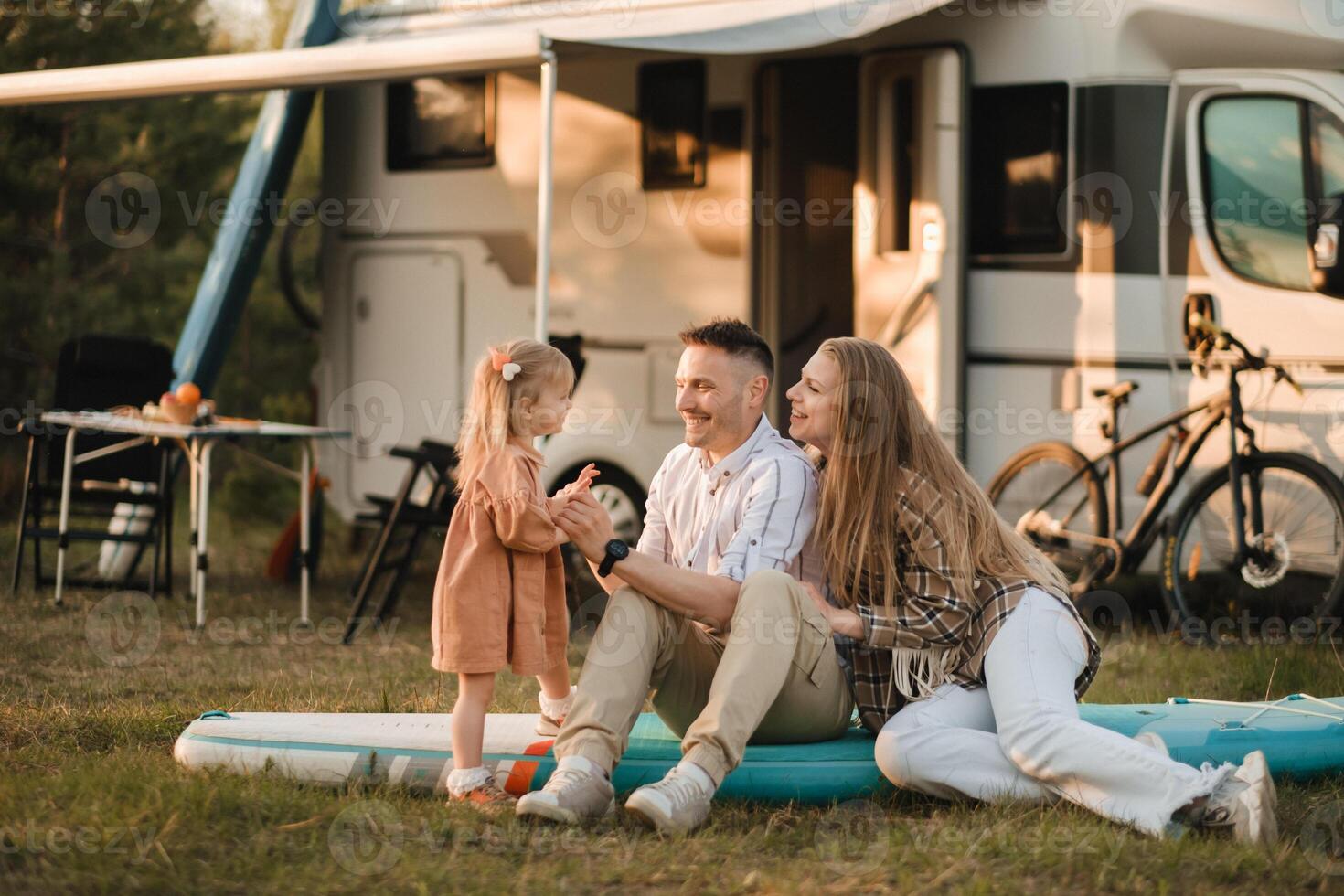 a young family is sitting on a sup board next to their mobile home photo