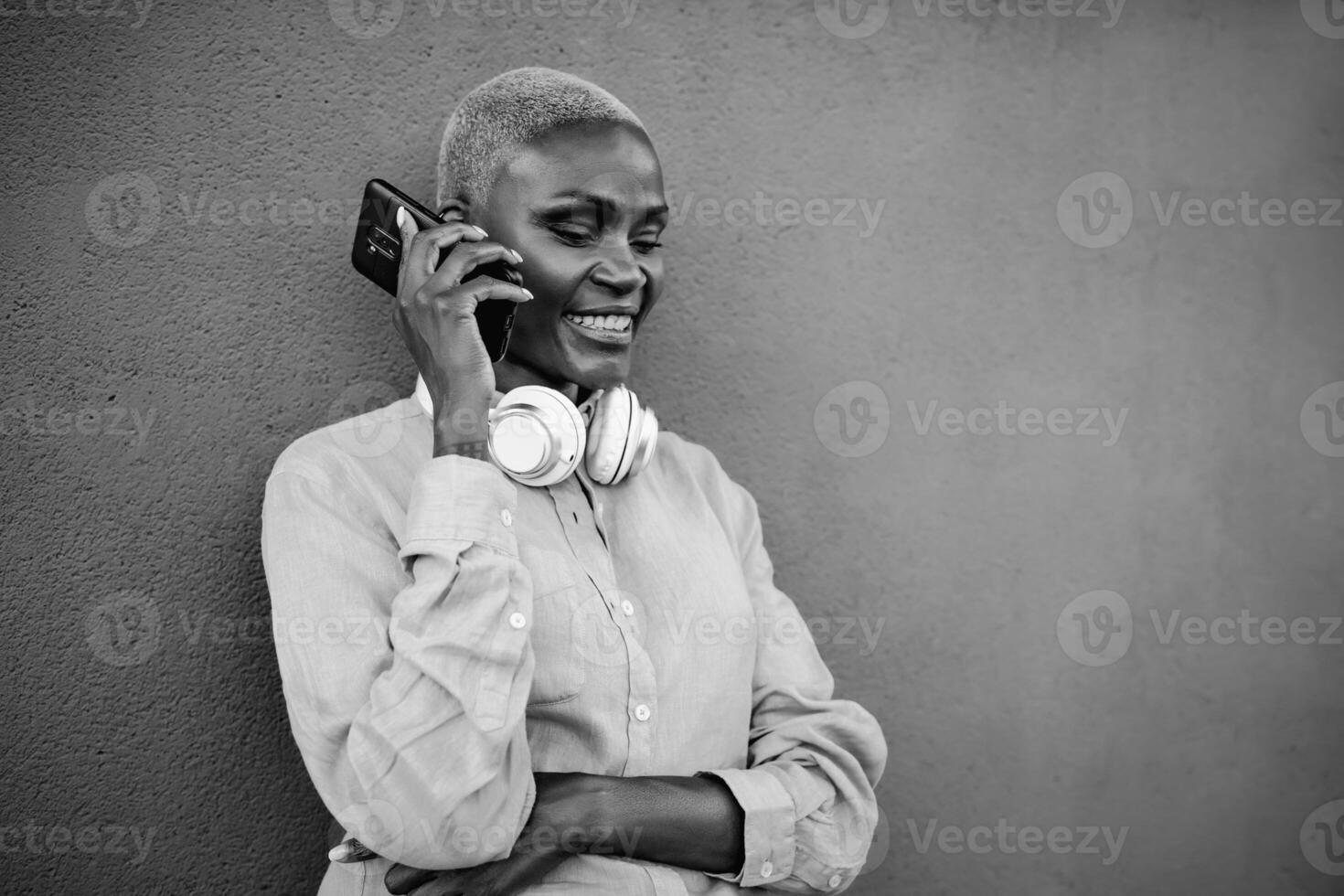 Happy smiling African woman doing a call with mobile smartphone outdoor - Black and white editing photo