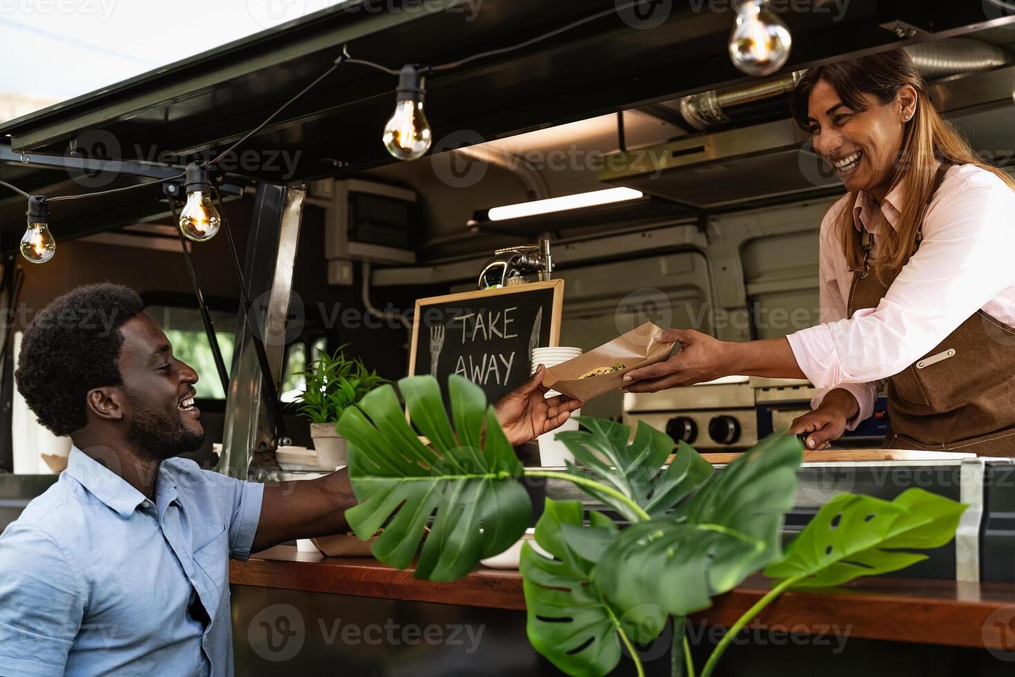 Young African man buying meal from food truck - Modern business and take away concept photo