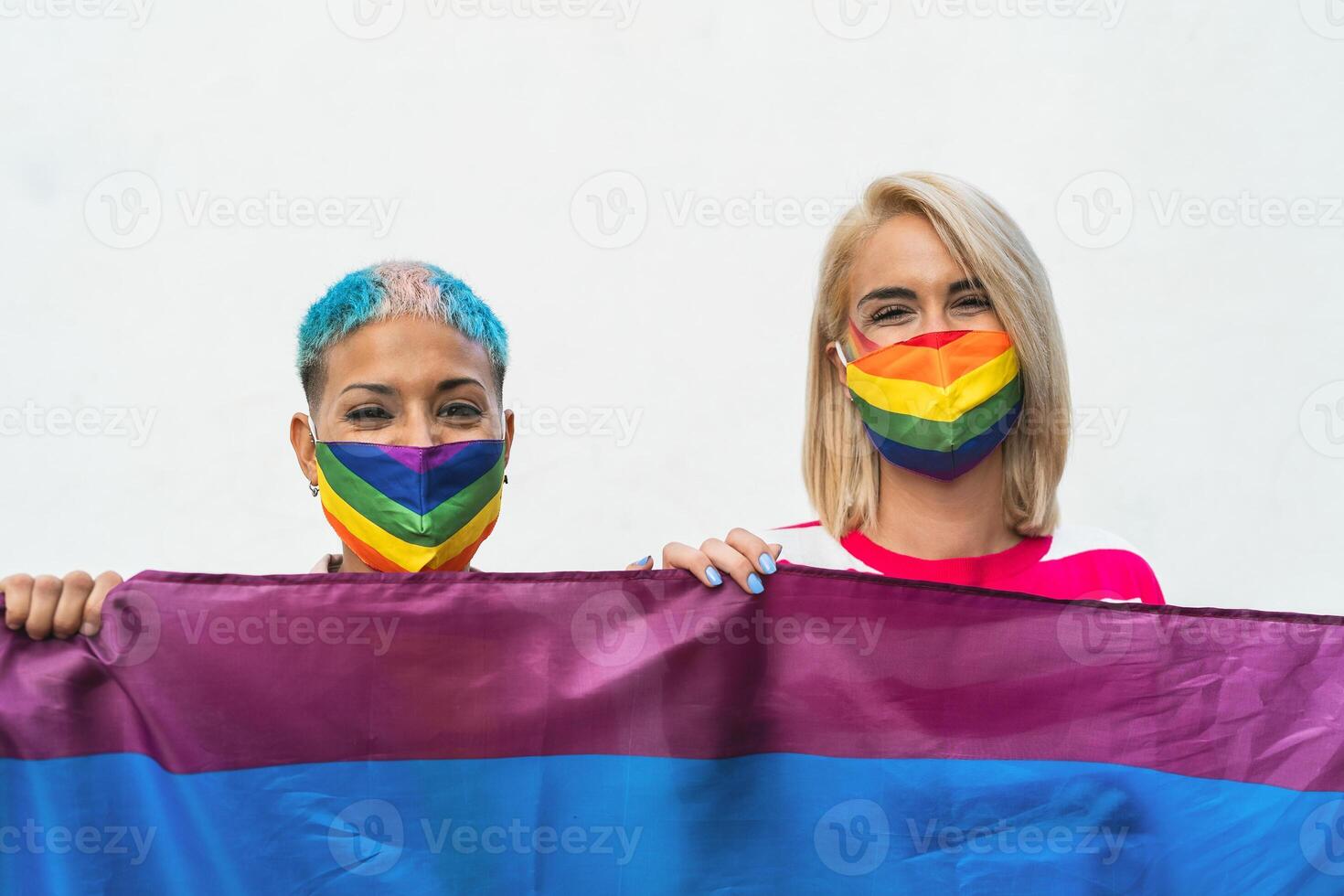 Happy gay couple wearing face mask celebrating gay pride event during corona virus pandemic photo