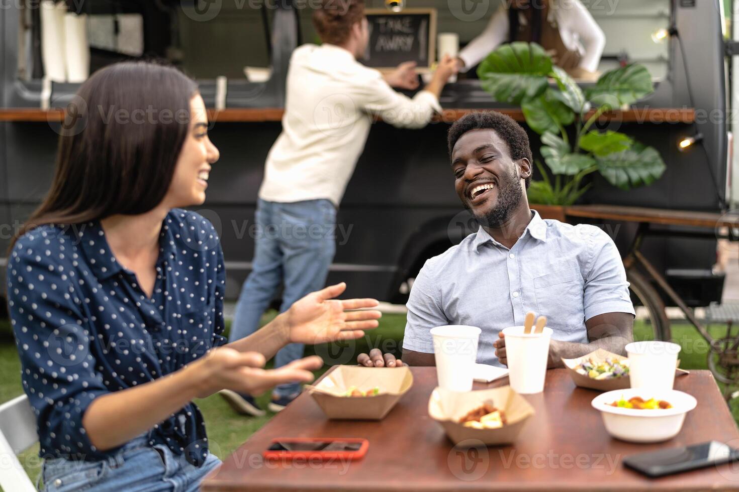 Happy multiracial friends having fun eating in a street food truck market photo
