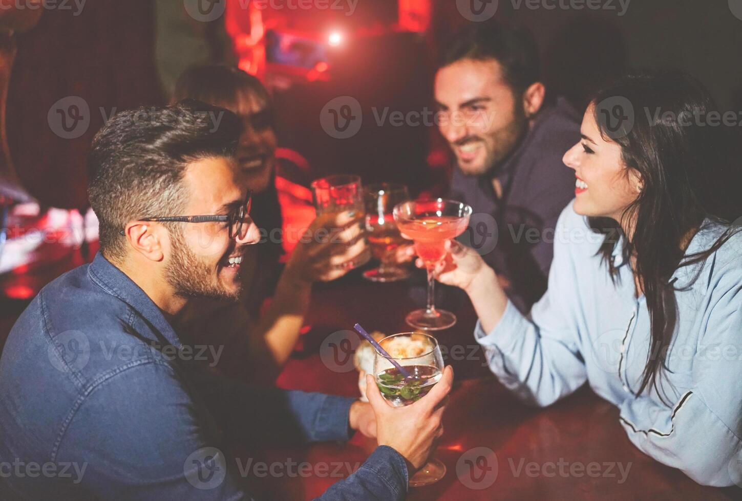 contento amigos Bebiendo y tostado cócteles en un jazz bar - joven personas aplausos y riendo juntos en un club a noche - amistad, estilo de vida, la vida nocturna concepto foto