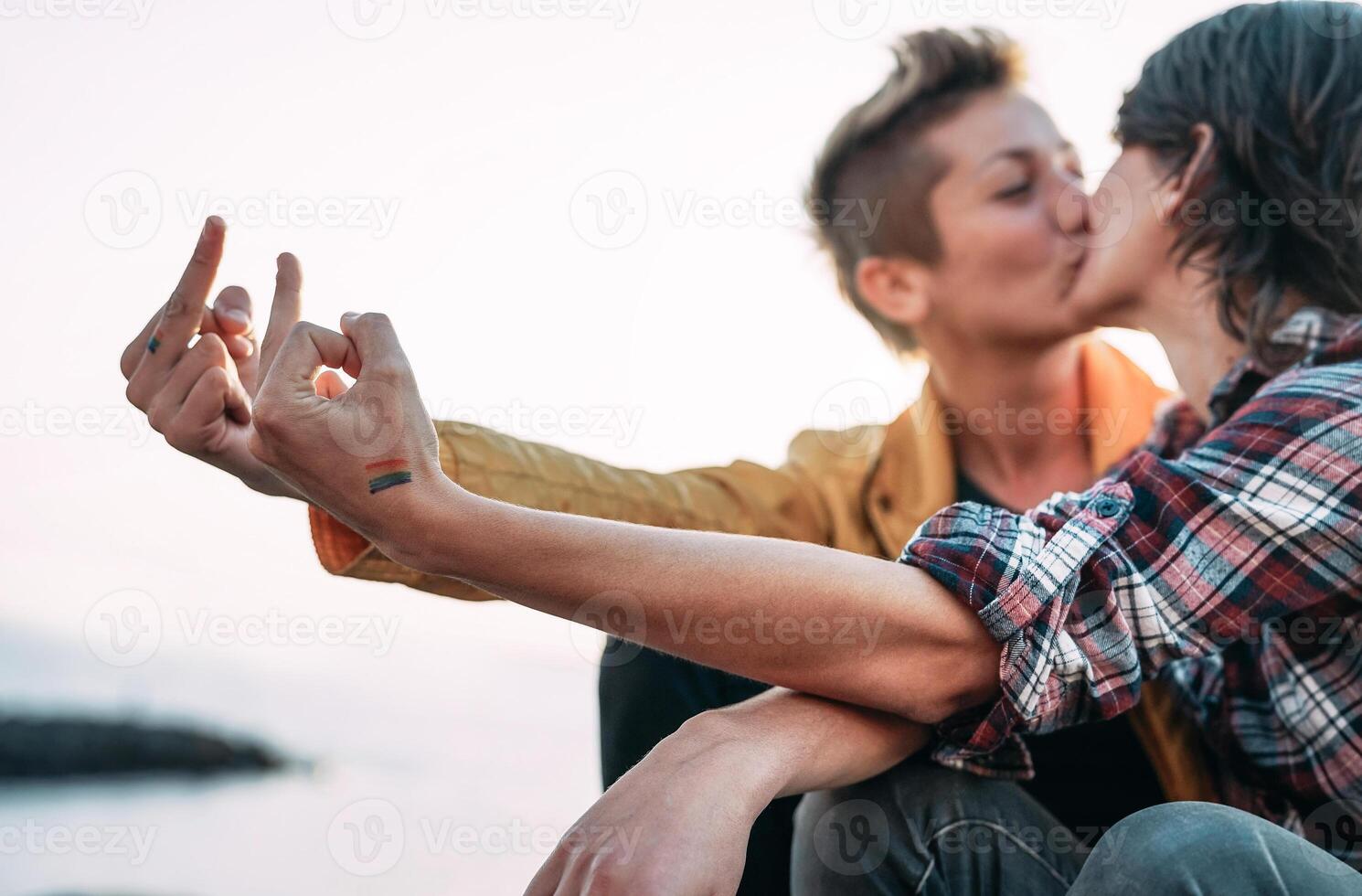 Lesbian couple kissing while celebrating lgbt pride - Gay lover having tender moments on the beach - homosexuality, pride and relationship lifestyle concept photo