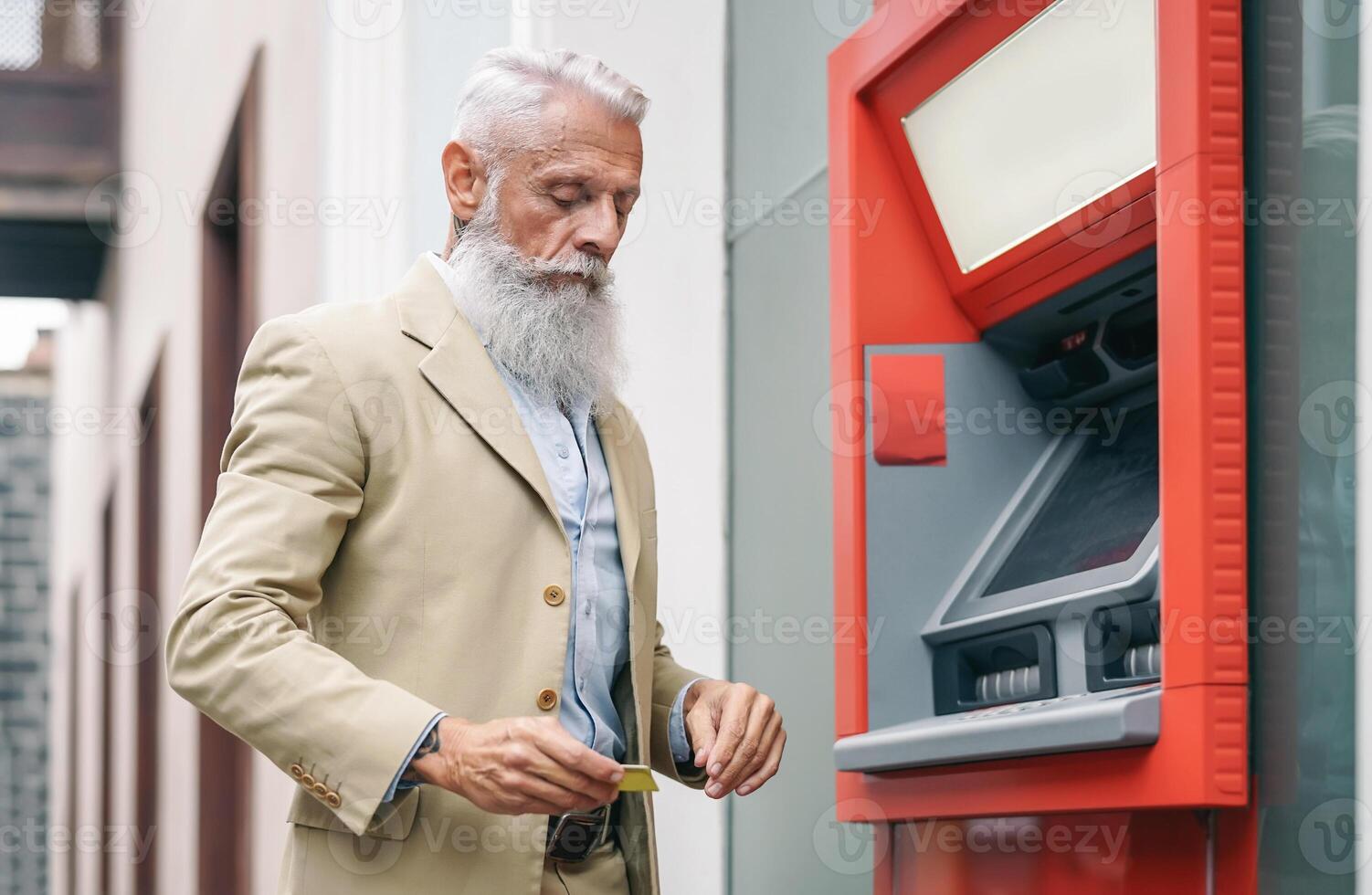 mayor hombre retirar dinero desde banco efectivo máquina con débito tarjeta - barbado hipster maduro masculino haciendo pago con crédito tarjeta en Cajero automático - concepto de negocio, bancario cuenta y mayor estilo de vida personas foto