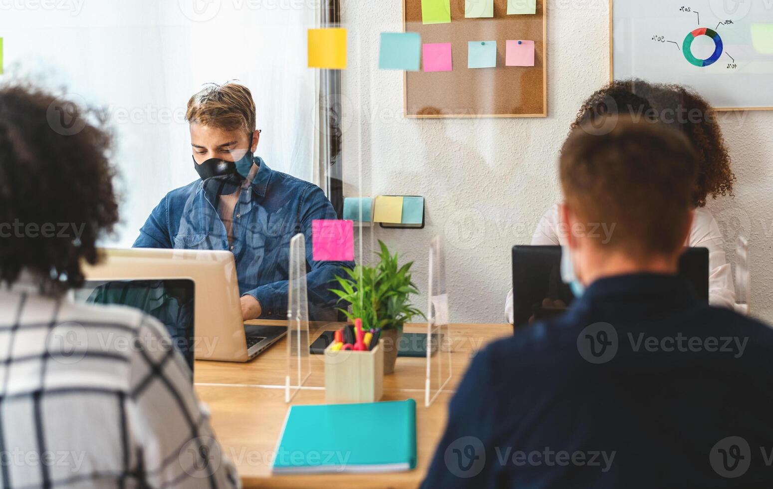 Young people in co-working creative space wearing surgical mask and keeping social distance to avoid corona virus spread - Health care and business technology concept photo