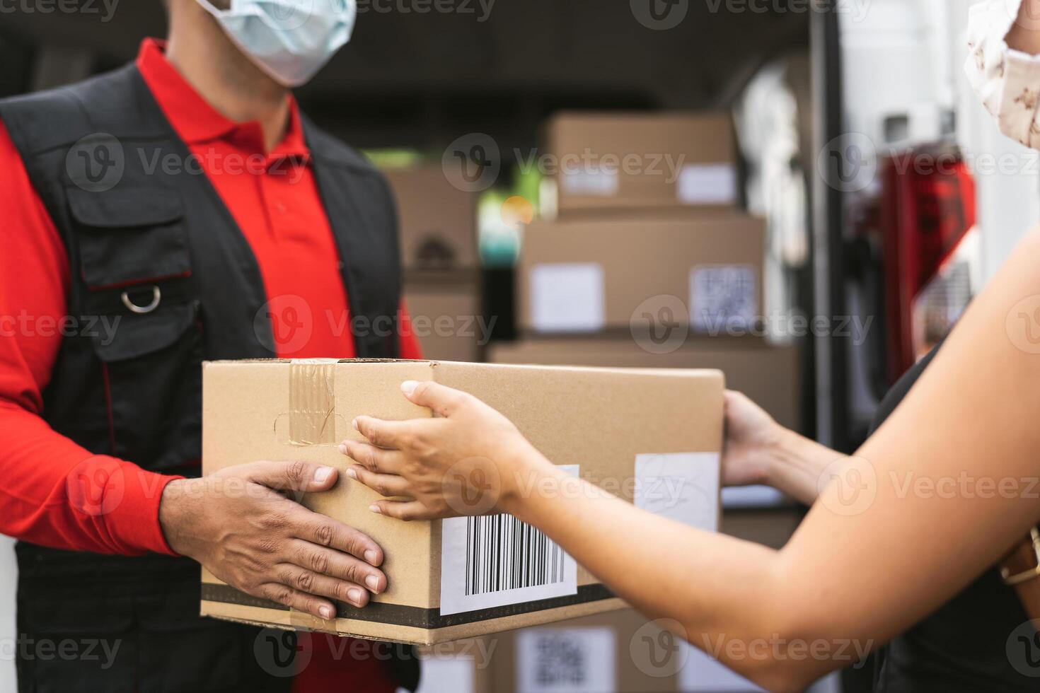 Delivery man wearing face protective mask to avoid corona virus spread - Young woman receiving an online order package from courier express photo